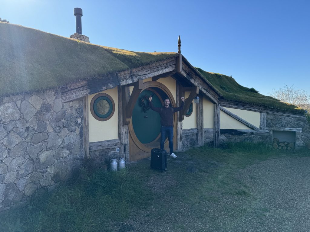 Exterior de una casita de La Comarca de Veratton con tejado de hierba y puerta redonda verde