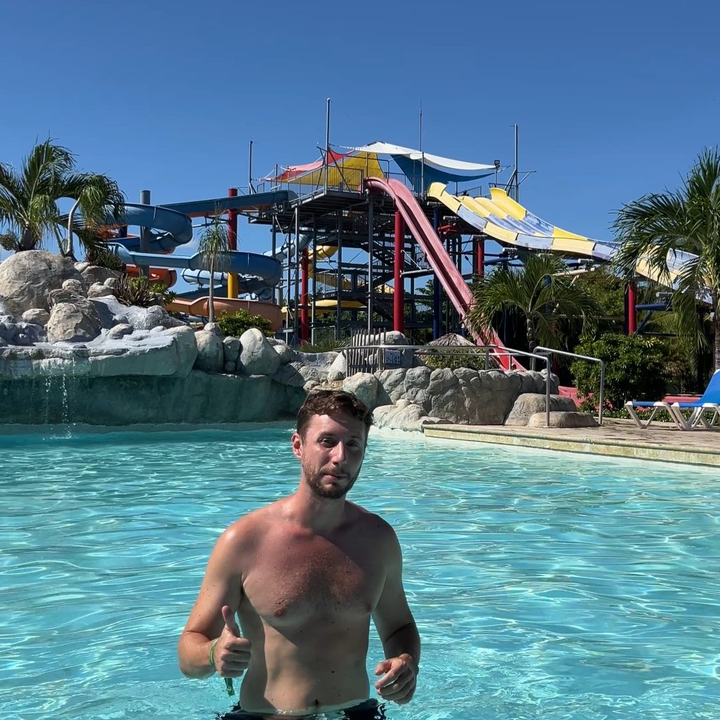 Foto en la piscina con el parque acuñatico detrás en el hotel Grand Sirenis