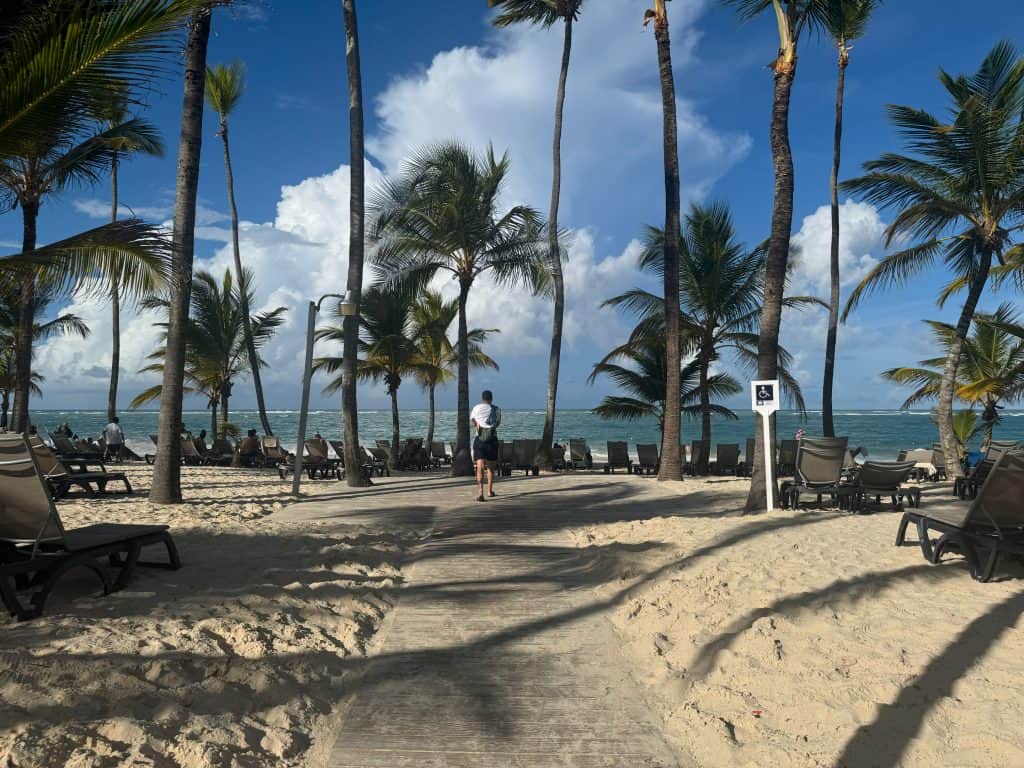 Beach with palm trees, lounge chairs, and clear blue sky at a tropical resort.