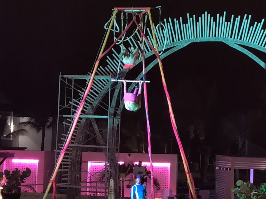 Colorful illuminated swings at night with pink lighting and people enjoying the amusement park ride.