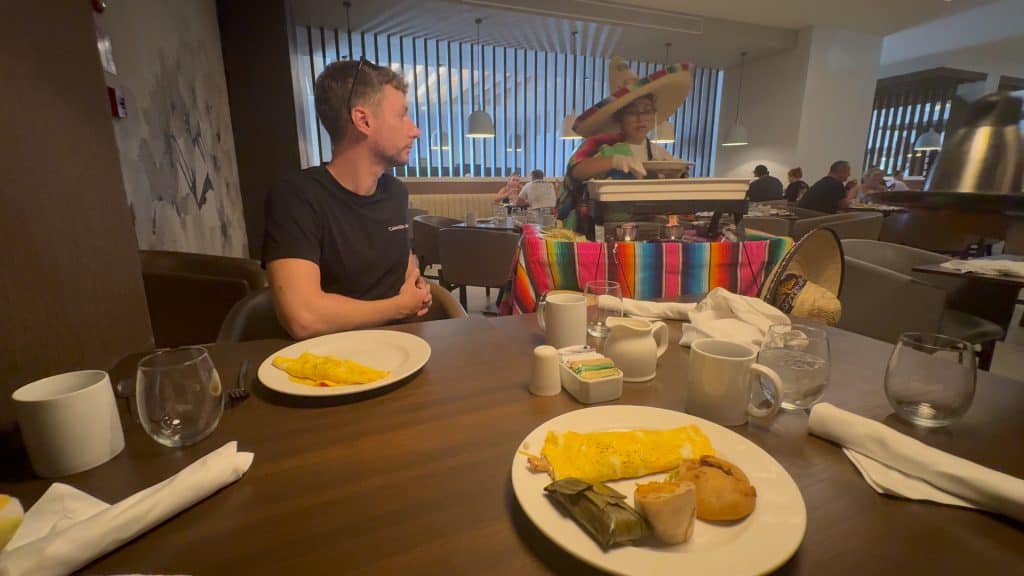 Colorful Mexican waitress serving breakfast in a modern hotel restaurant.