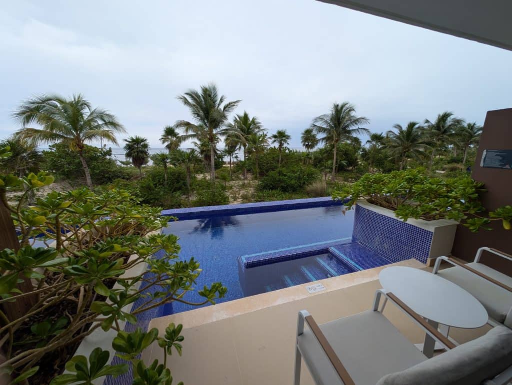 Luxurious infinity pool with lush tropical trees and ocean view in the distance.