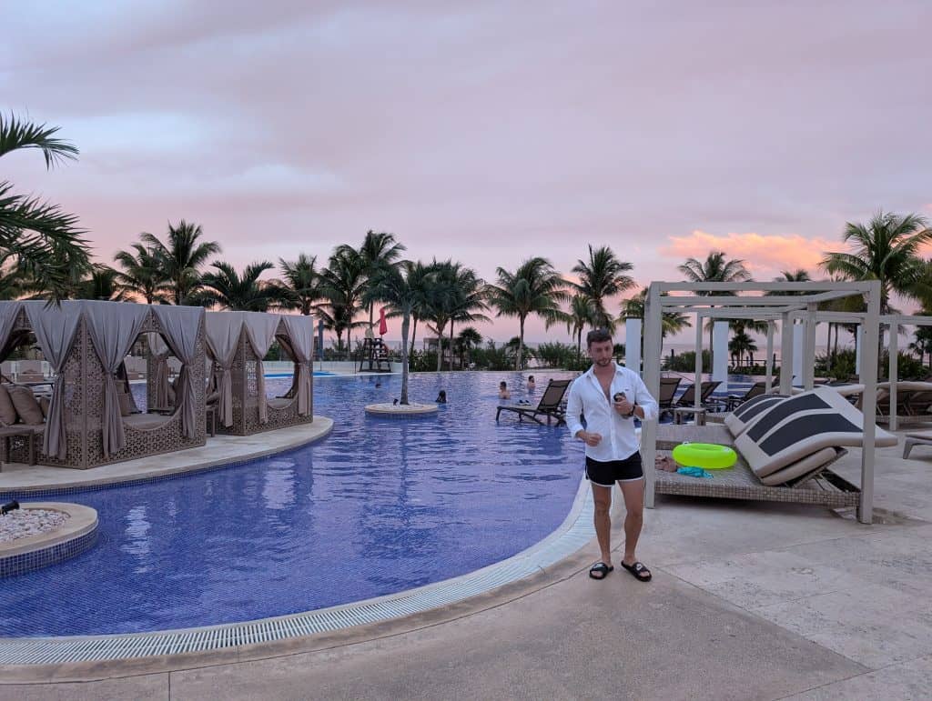 Luxurious infinity pool at sunset with palm trees in the background, tropical resort setting.