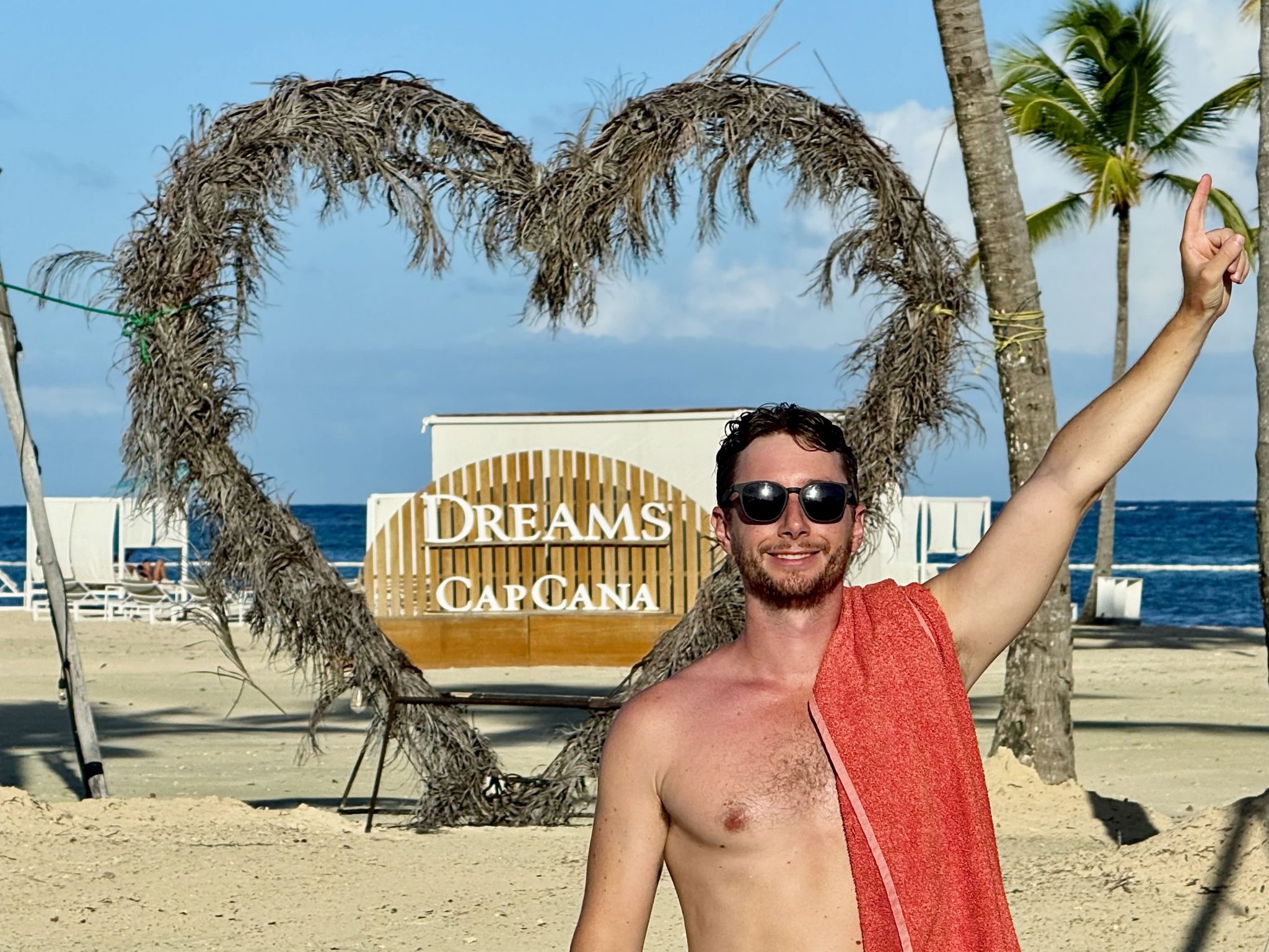 Cartel del Dreams Cap Cana en la playa, bajo un corazón hecho con ramas de palmera