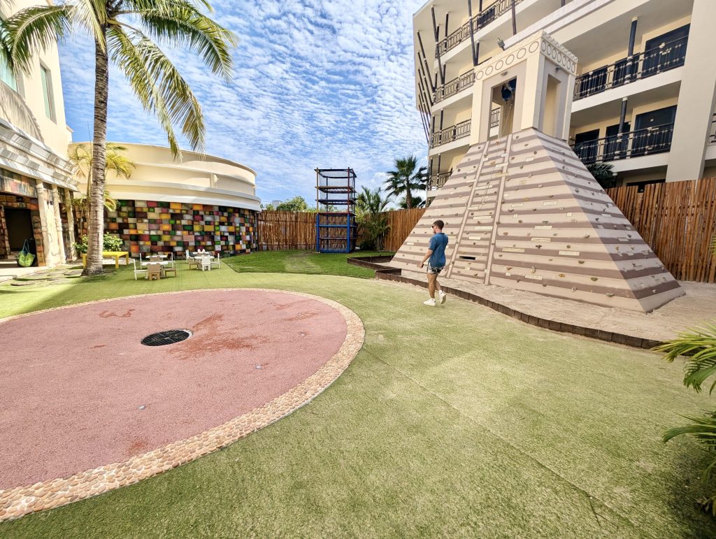 Zona de juegos ajardinada con torre de escalada en el Dreams Riviera Cancún