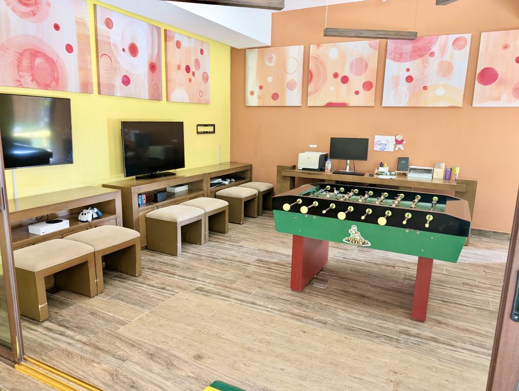 Zona tecnológica del club infantil con futbolín y videoconsolas