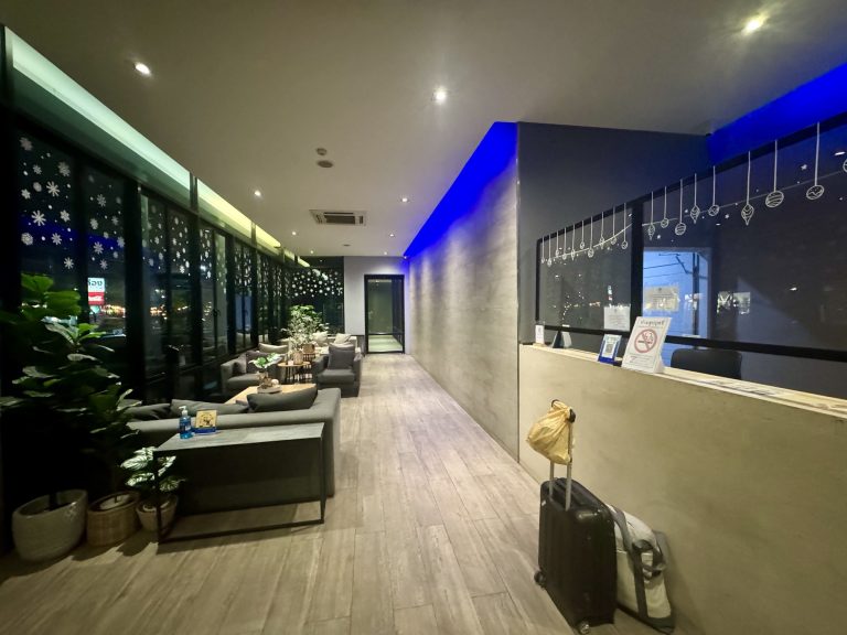 Recepción y zona de sofás del HUG Nimman de noche, con los ventanales a la calle