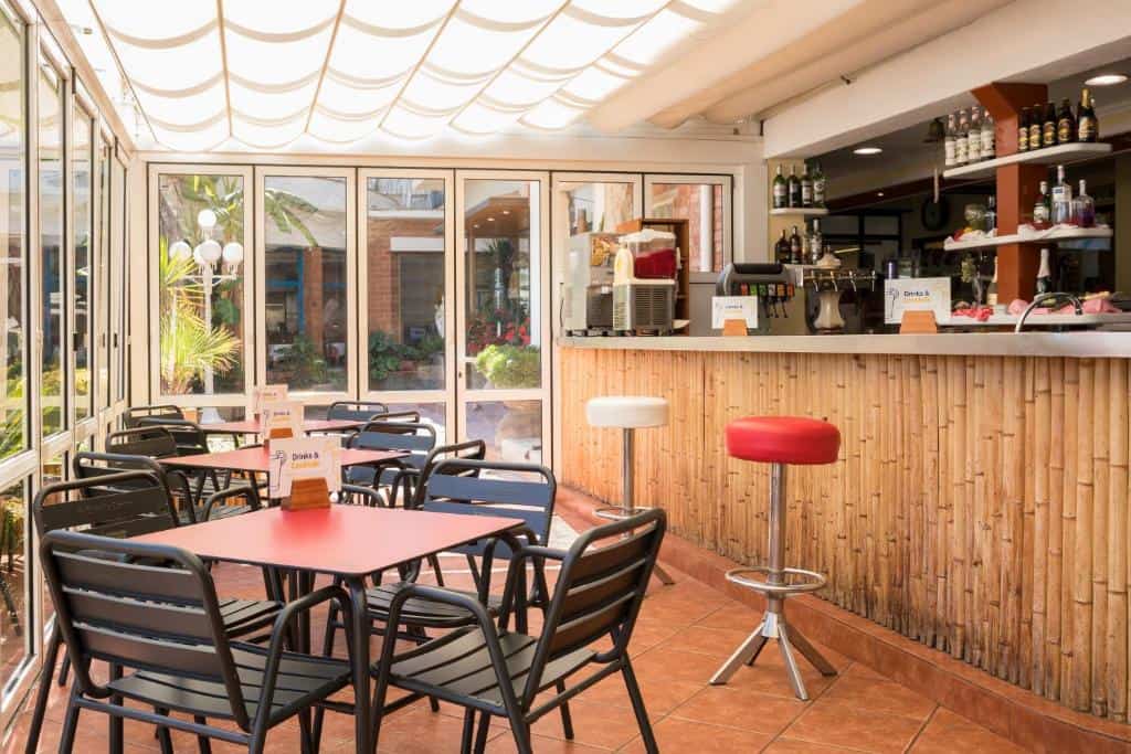 Bright indoor cafe with pink tables, black chairs, and a bamboo counter bar.