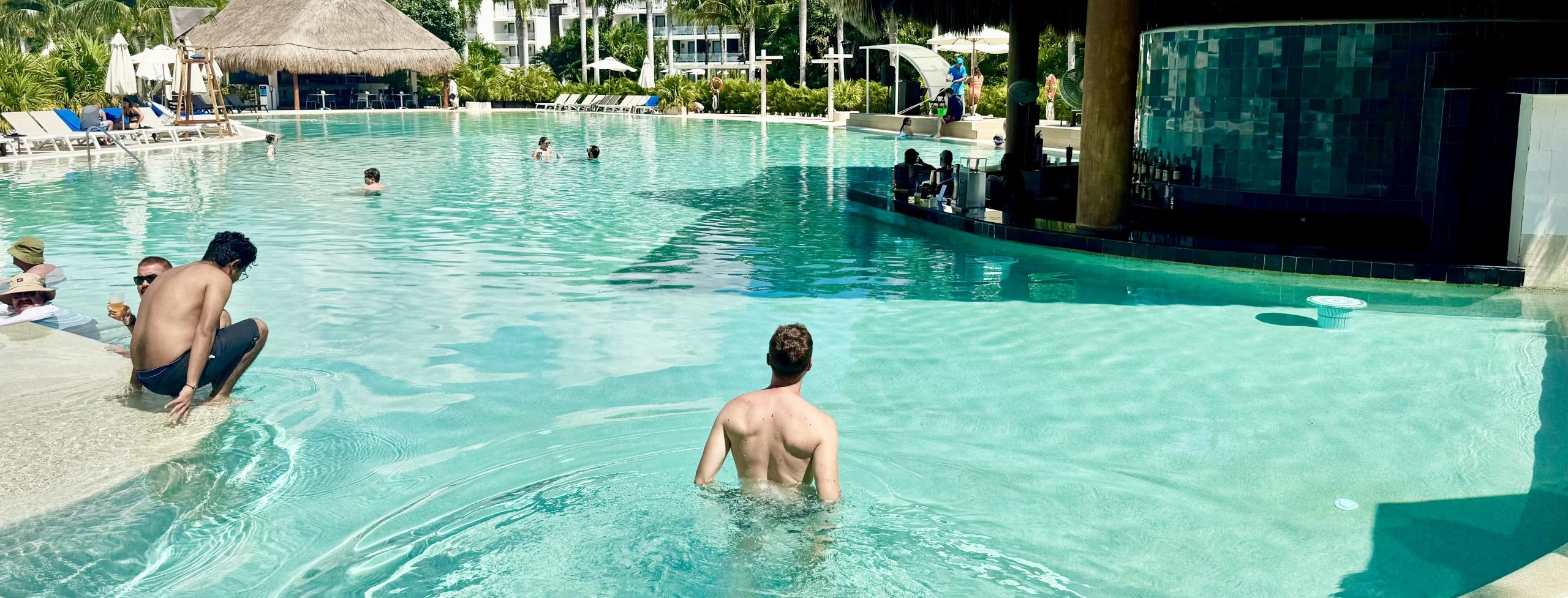 Poolside relaxation at a tropical resort with thatched roofs and lush surroundings.