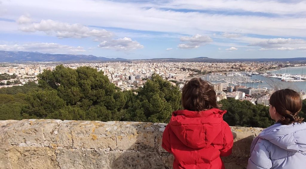 Children overlooking a scenic city and harbor view from a lookout point in Barcelona, Spain.