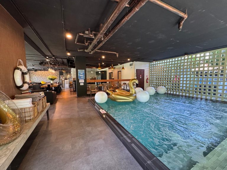 Piscina interior del ECHO Hotel en Santitham, con flotador dorado y las tuberías vistas