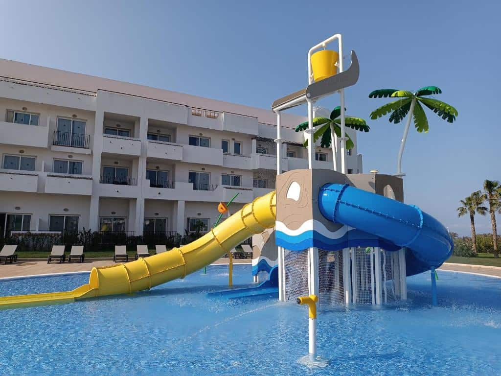 Colorful water slide at a hotel pool area with a white building in the background.