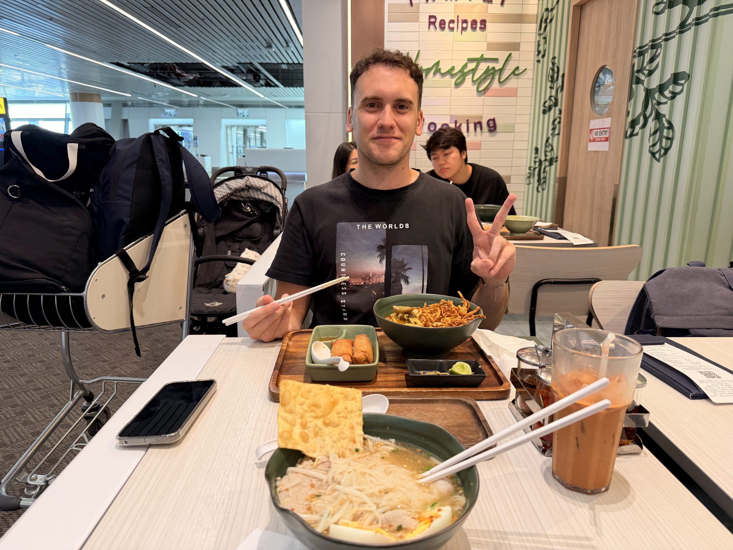 Víctor con una bandeja de comida tailandesa y un Khao Soi en un local dentro del aeropuerto de Suvarnabhumi