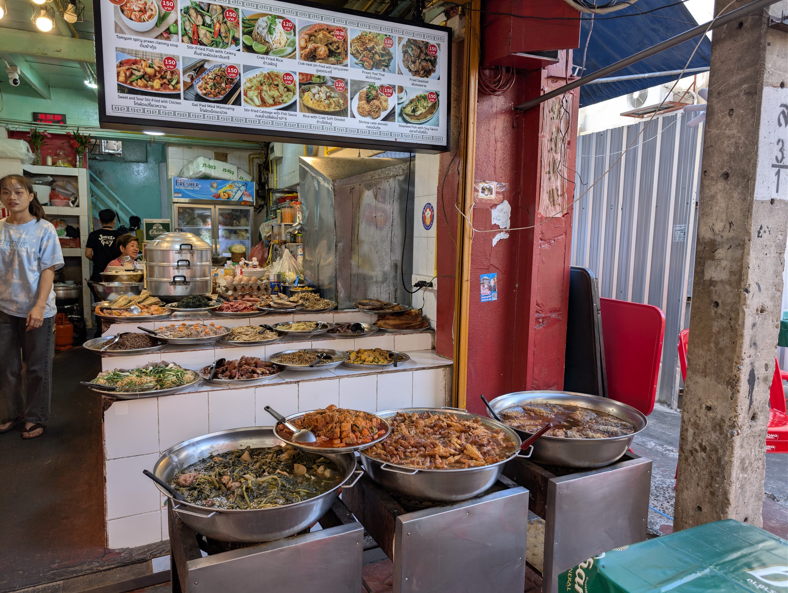 Puesto de guisos en Chinatown con las bandejas metálicas a la vista y la carta iluminada con las fotos de los platos encima