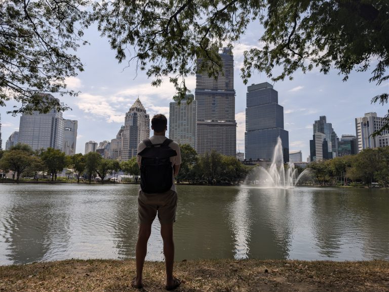 El lago del parque Lumphini con los rascacielos de Bangkok al fondo y la fuente en el centro