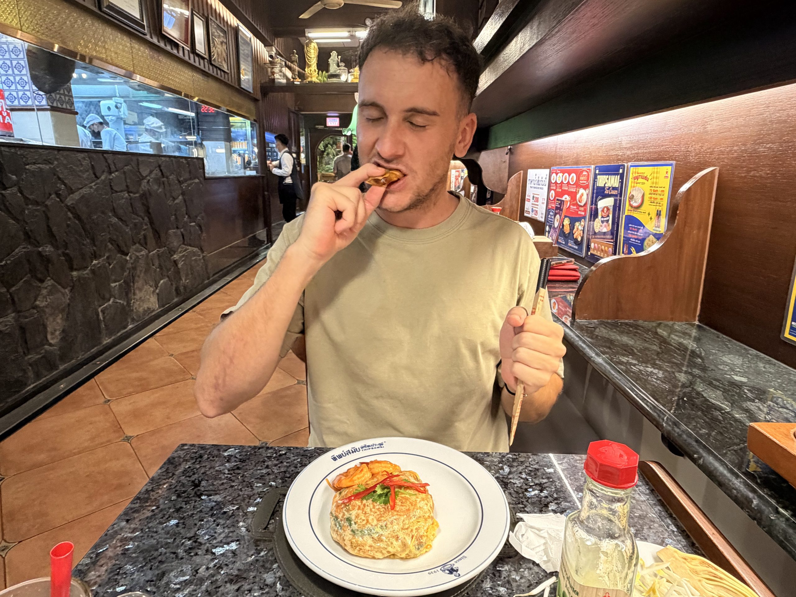 Víctor comiendo en la barra de Thipsamai, con el Pad Thai envuelto en tortilla de huevo en el plato