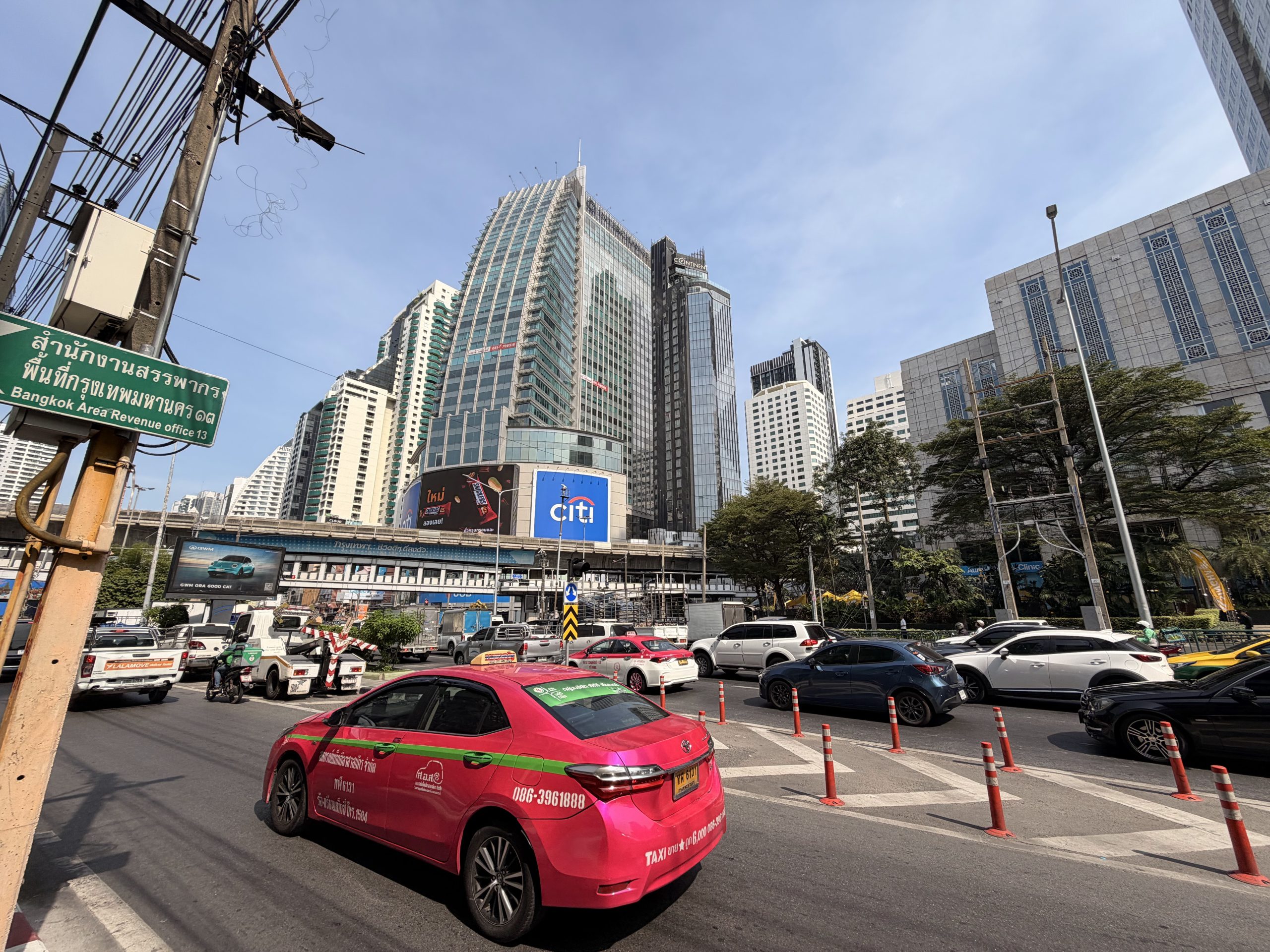 Taxi rosa de Bangkok parado en una avenida del distrito financiero, con los rascacielos al fondo
