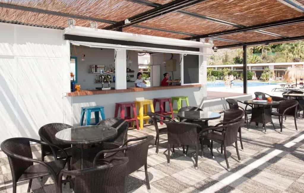 Outdoor bar area with colorful stools and seating at a poolside resort.
