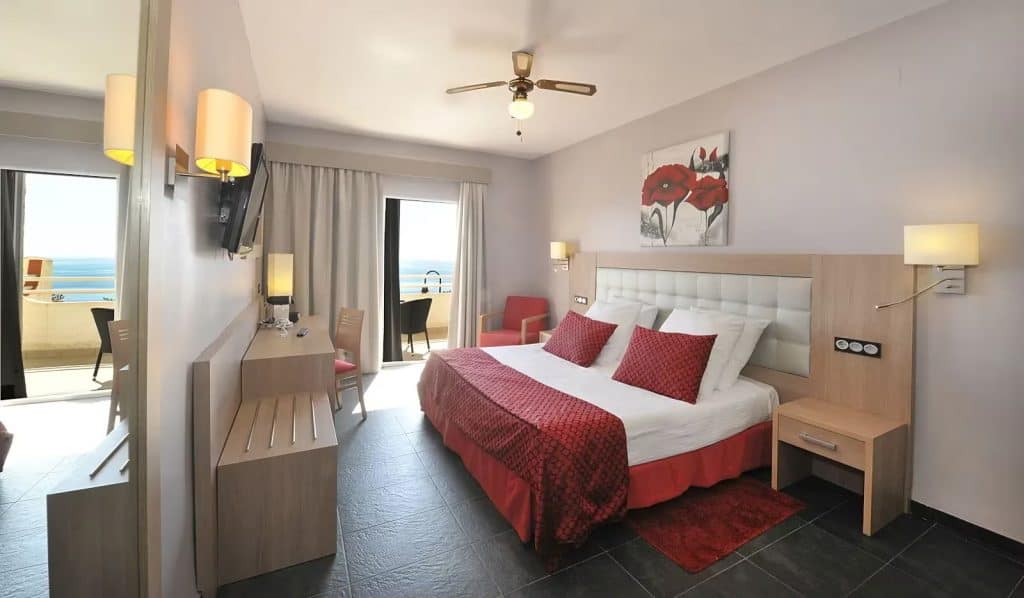 Beachfront hotel room with balcony, sea view, modern decor, and comfortable bed.