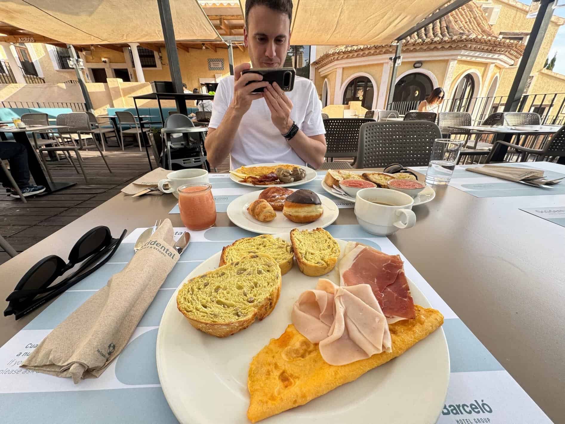 Javier Sobrino fotografiando su desayuno en la terraza del Occidental Pueblo Acantilado, con tortilla, jamón y tostadas