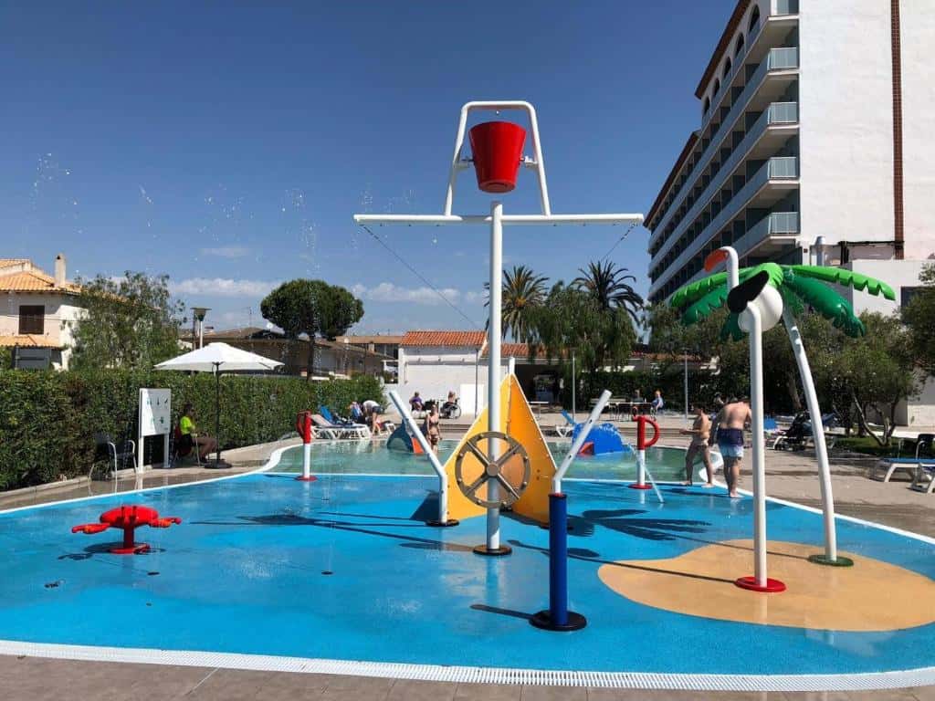Splash pad with water play features and colorful equipment in an outdoor pool area.