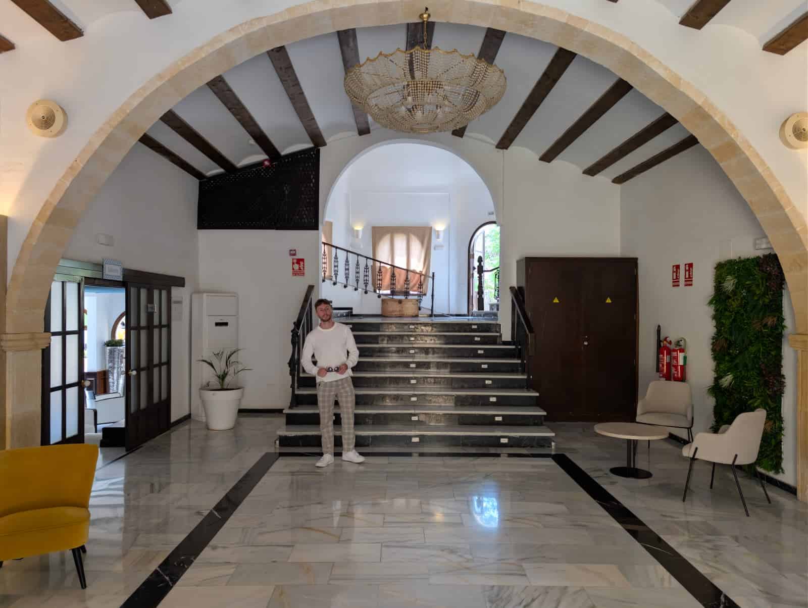 La recepción del Occidental Pueblo Acantilado, con un arco de piedra, vigas de madera y la escalera al fondo