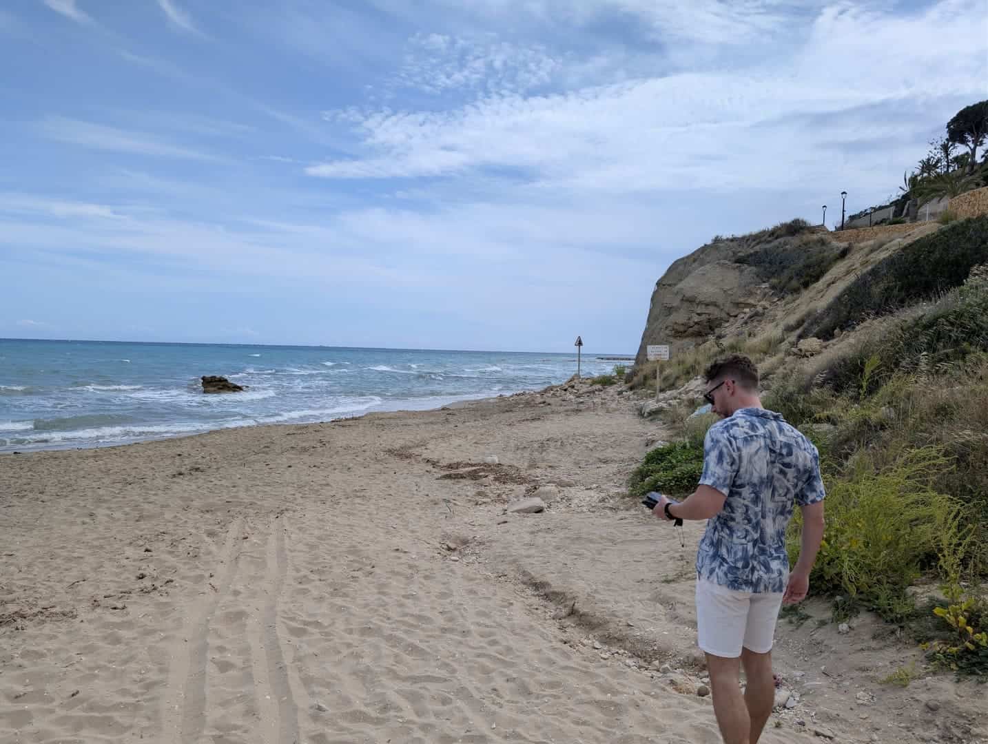 Javier Sobrino caminando por una playa de arena bajo el acantilado, cerca del Occidental Pueblo Acantilado