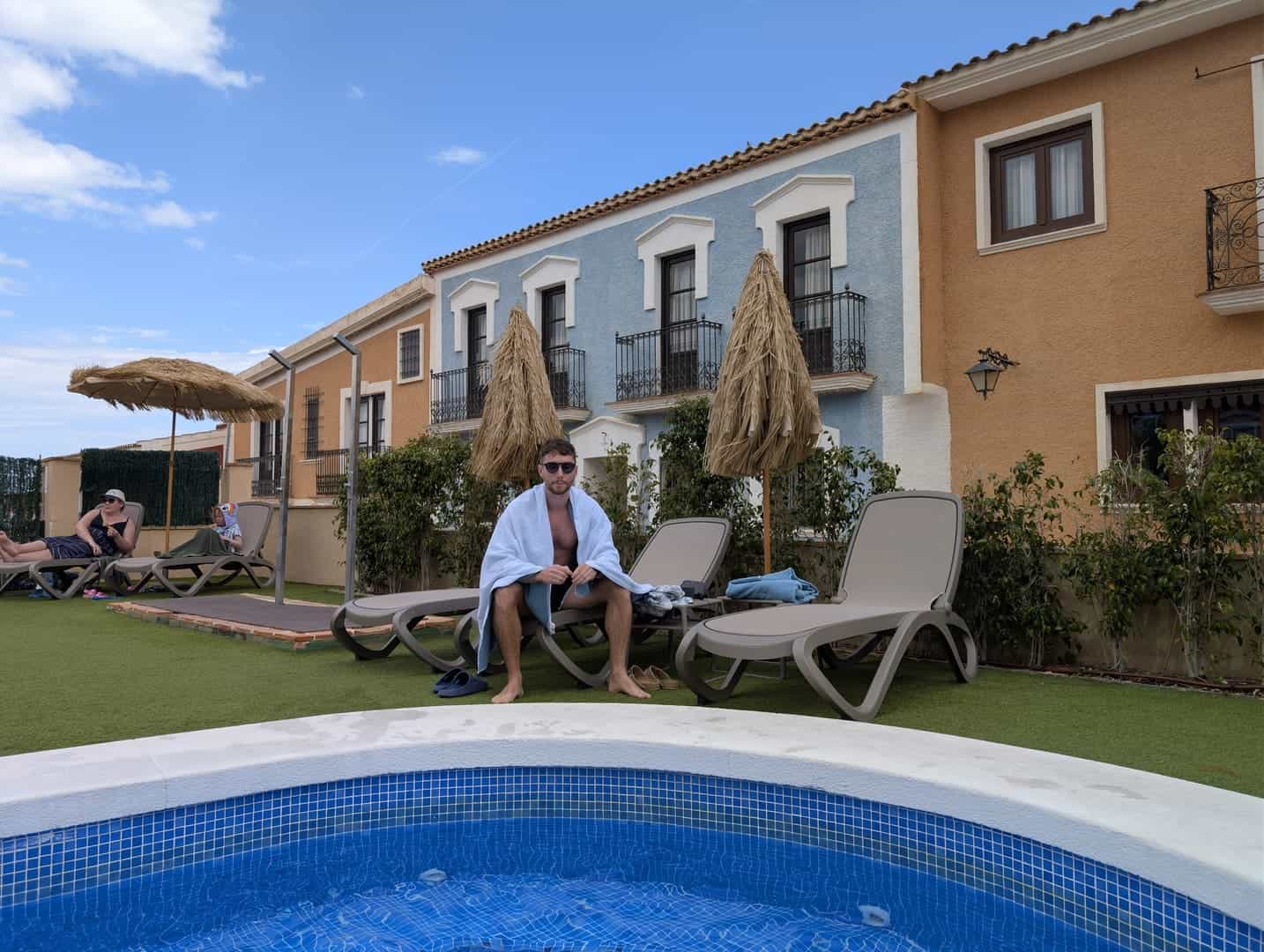 Javier Sobrino en una tumbona junto a la piscina del Occidental Pueblo Acantilado, bajo una sombrilla de paja