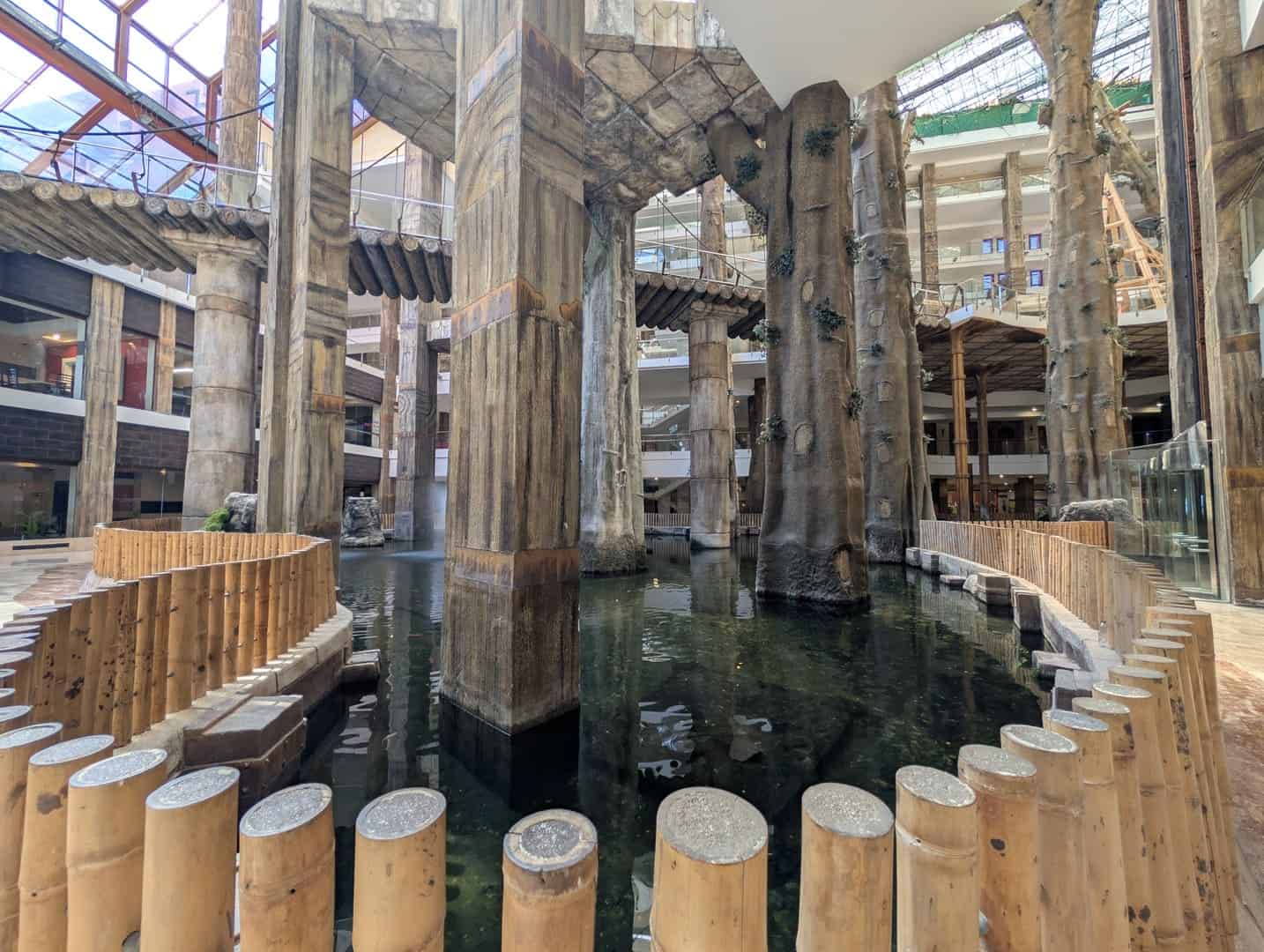 A lush indoor water feature with wooden and stone elements in a modern architectural space.