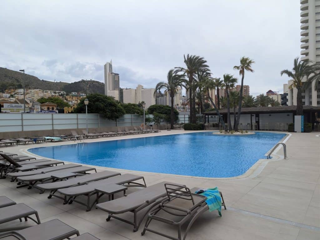 Zona de hamacas junto a la piscina del BCL Levante Club, con Benidorm al fondo