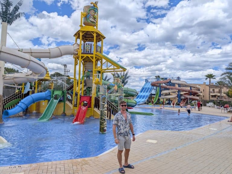 A colorful water park with multiple slides and a large pool under a partly cloudy sky.