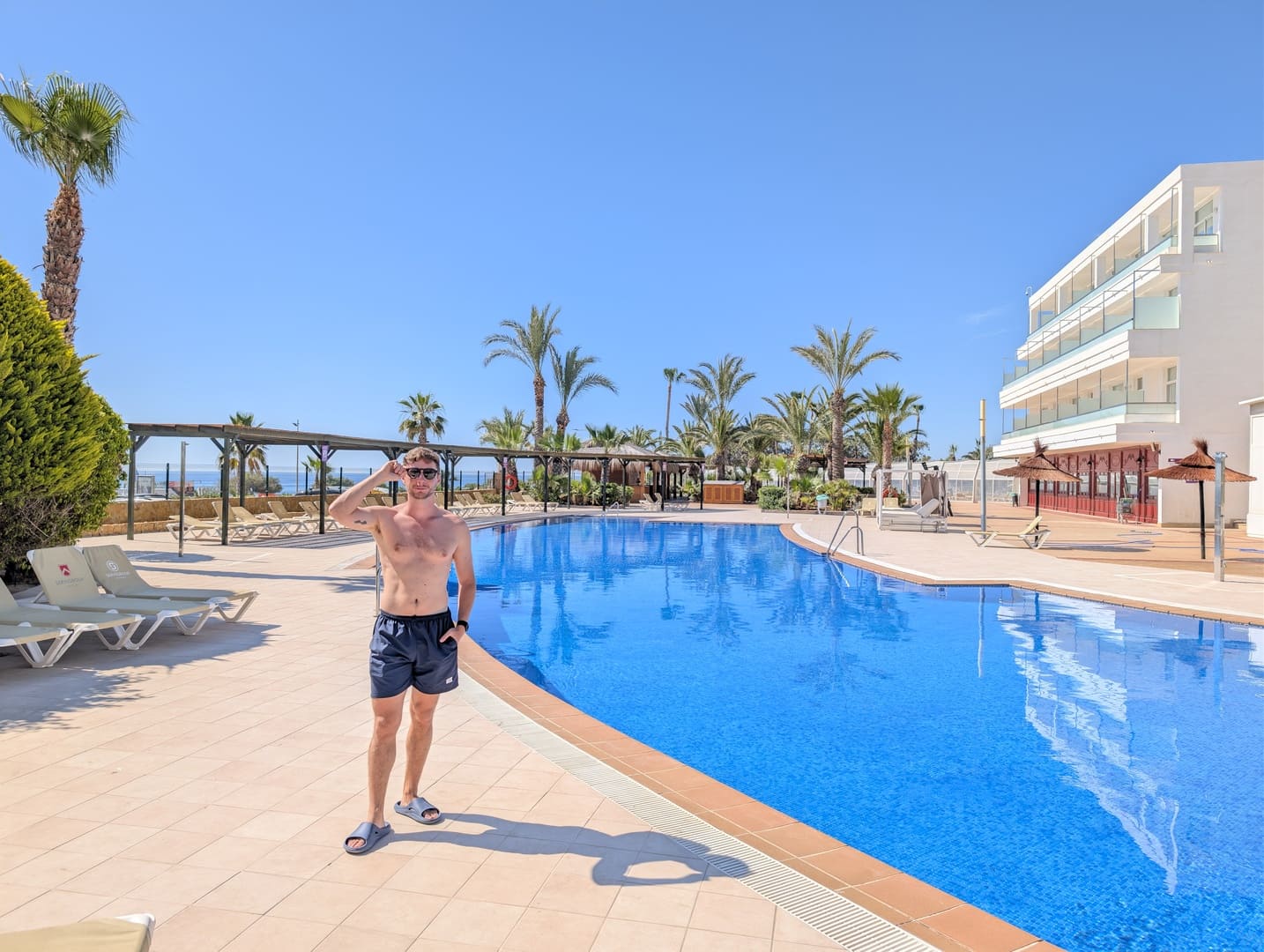 Zona de tumbonas y palmeras junto a la piscina del Servigroup Marina Playa
