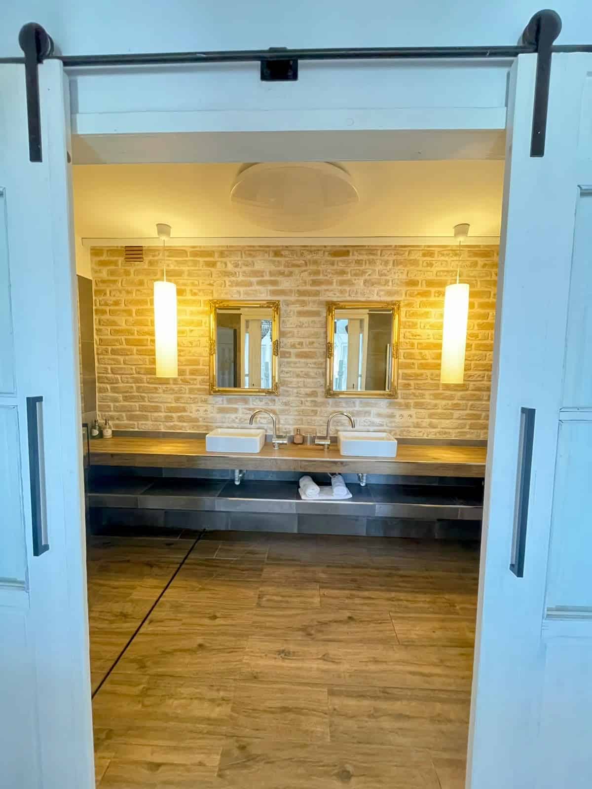 Puertas correderas de acceso al baño con pared de ladrillo