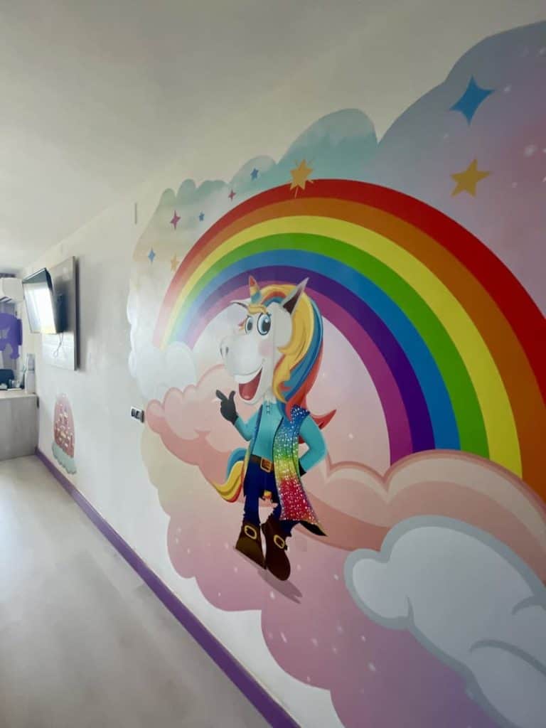 Mural de un unicornio sobre un arcoíris en la pared de una habitación Rainbow del Magic Fantasy