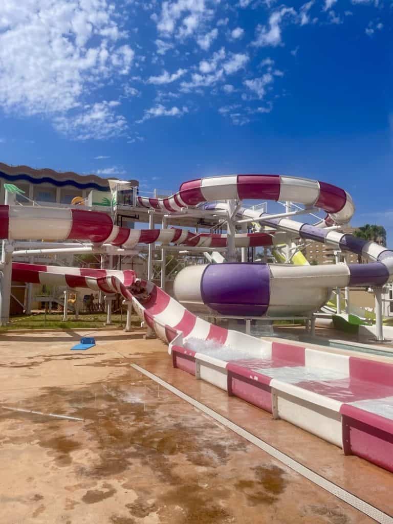Toboganes grandes rojo y morado del parque acuático Magic Splash vistos desde abajo