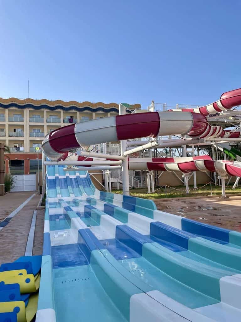 Toboganes multipista de colores del parque acuático Magic Splash, con el hotel al fondo