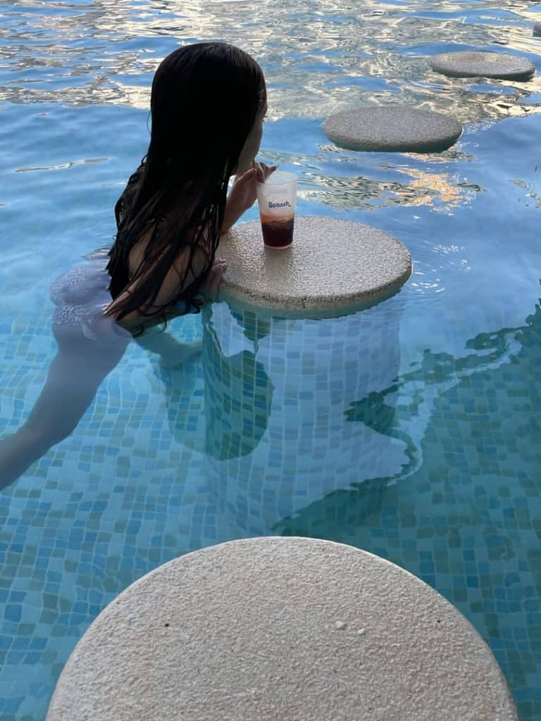 Niña apoyada en los taburetes dentro del agua del chiringuito de la piscina de Magic Splash