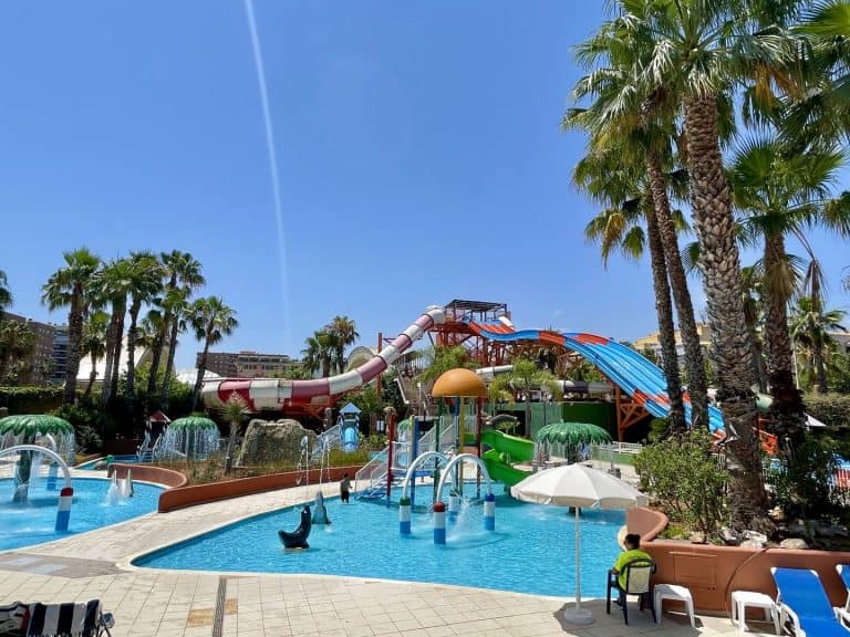 Vista general del parque acuático Polinesia con piscinas, palmeras y toboganes