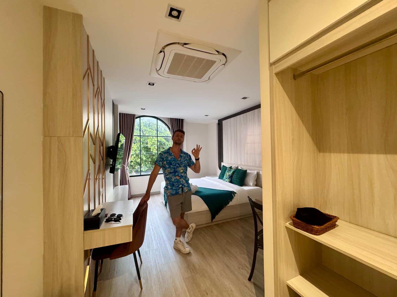 Habitación del Diff Apartel de Banglamphu, con ventana en arco y cama grande