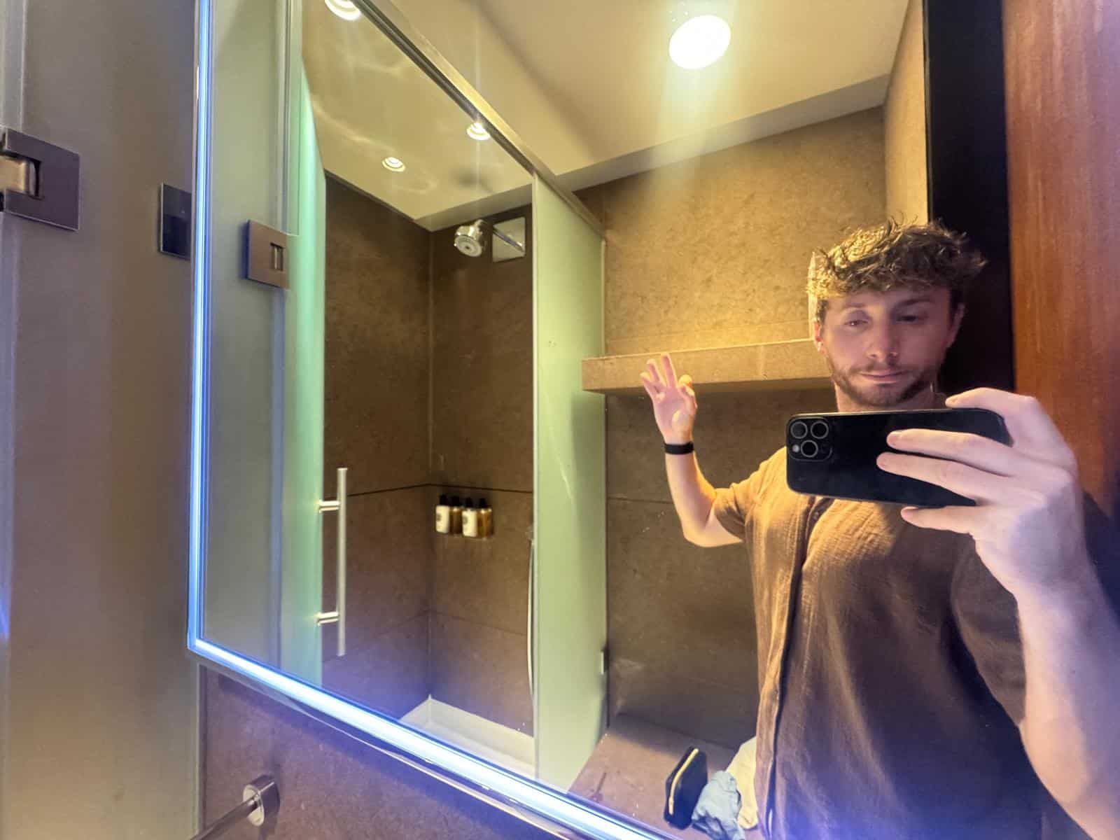 Cabina de ducha de la sala VIP de Doha, con mampara de cristal y amenities en una repisa