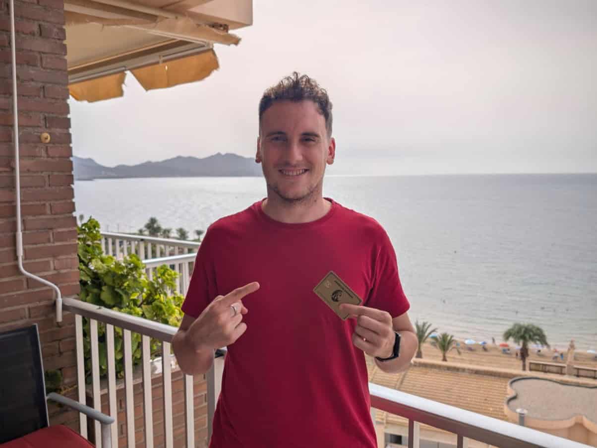 Víctor Redondo señalando su American Express Gold en un balcón frente al mar