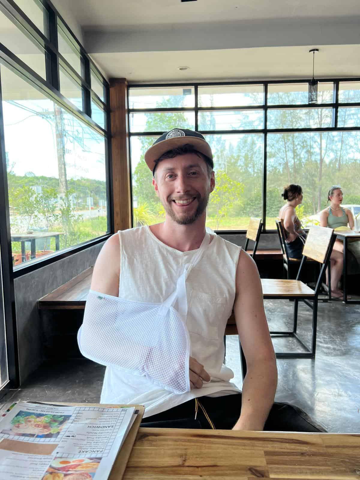 Javier Sobrino con el brazo en cabestrillo en una cafetería de Koh Lanta después del accidente que le pagó el seguro de Revolut Ultra