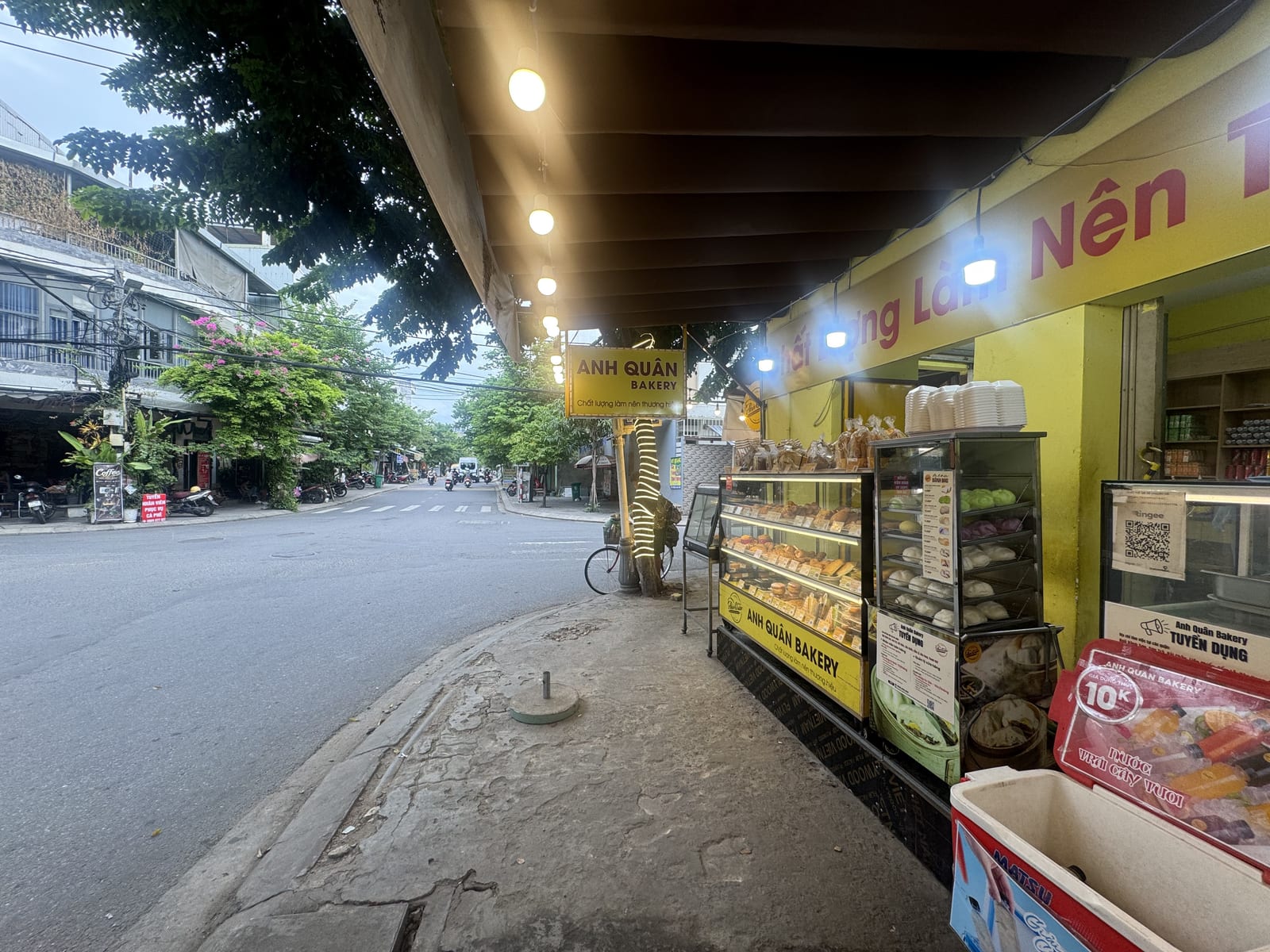 Puesto de bollería y comida en una calle de Da Nang, con el género en vitrinas y los precios a la vista