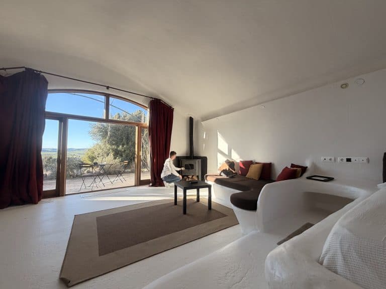 Interior de una cueva bioclimática del Hotel Spa Las Nubes con la cristalera y la estufa de leña encendiéndose