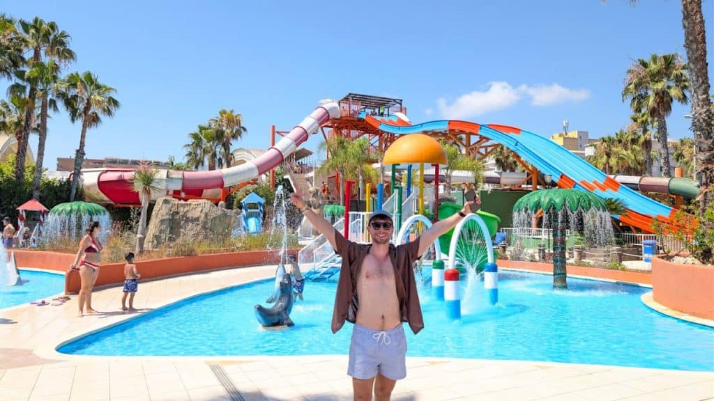 Family enjoying water slides and pools at a sunny water park.