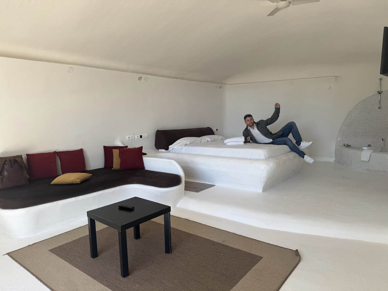 Interior de una cueva bioclimática del Hotel Spa Las Nubes con la cama, el sofá de obra y la bañera de hidromasaje