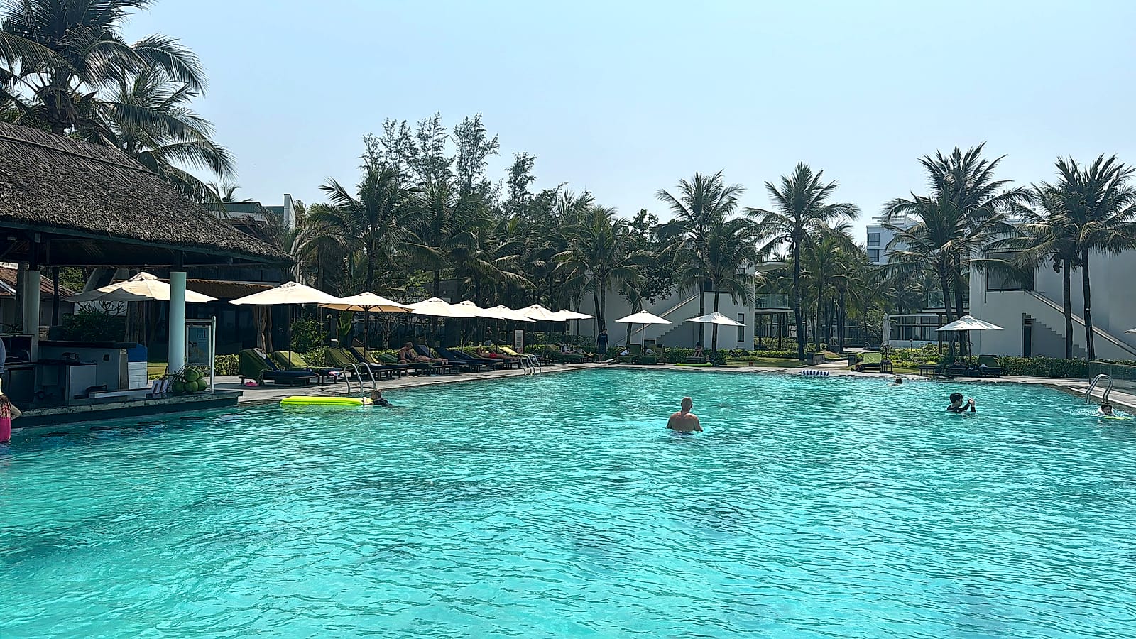 Piscina del Meliá Danang con palmeras y sombrillas