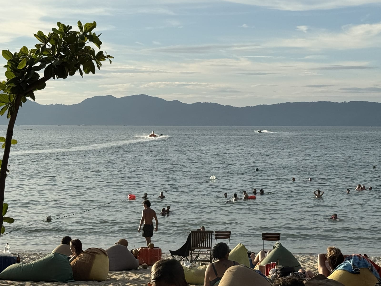 Playa de Da Nang con pufs y bañistas, y la montaña de Sơn Trà cerrando el fondo