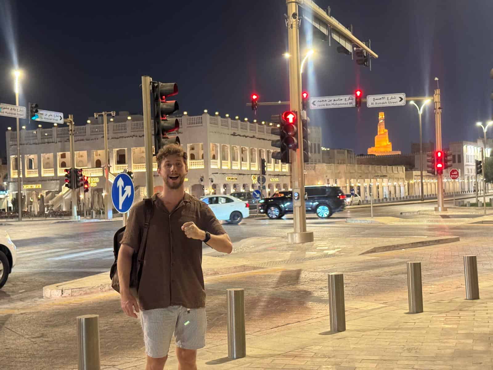Javier Sobrino de noche en una calle de Doha, con el minarete iluminado del Fanar al fondo