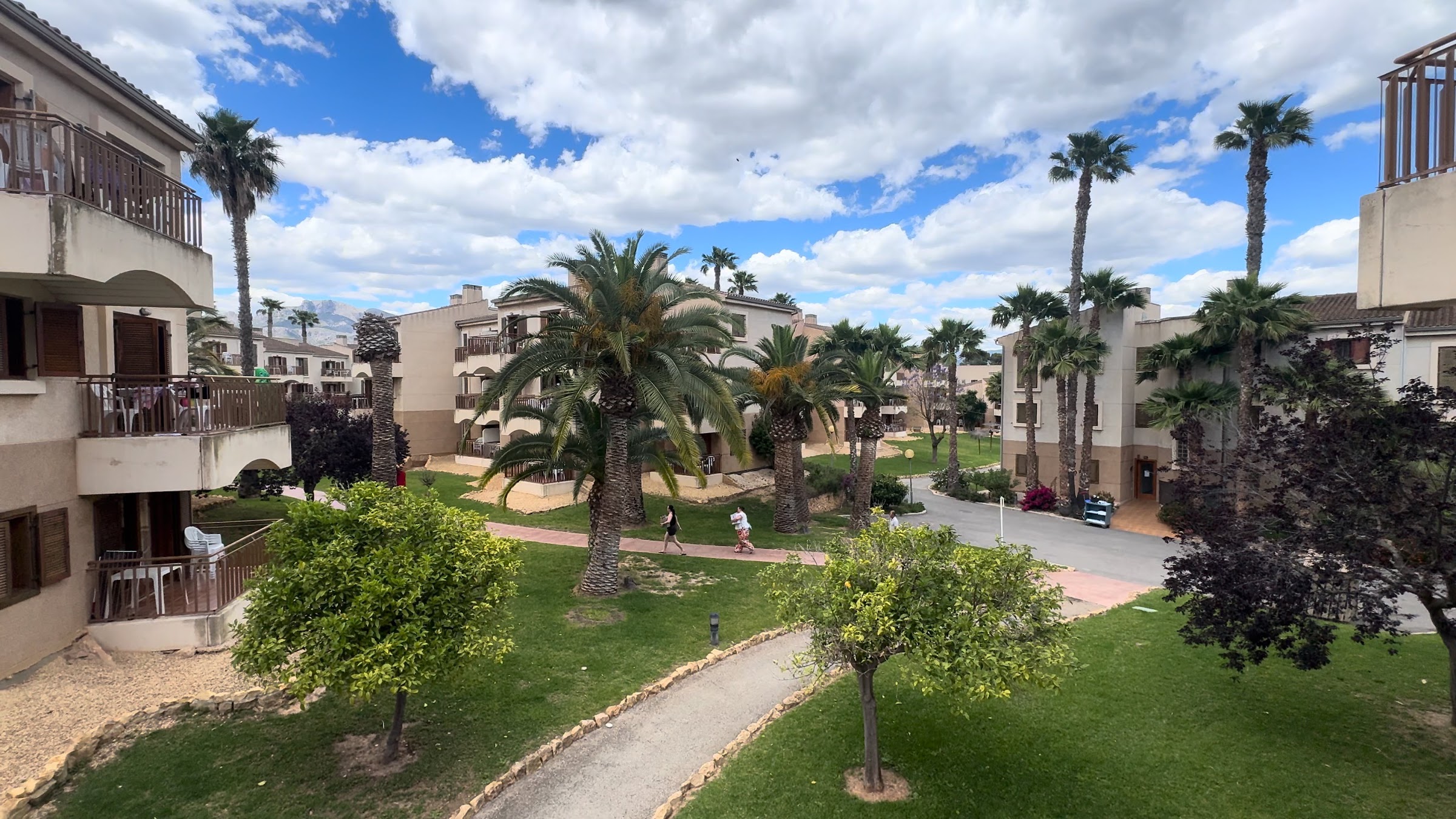 Jardines con palmeras y césped entre los edificios de apartamentos del Albir Garden Resort